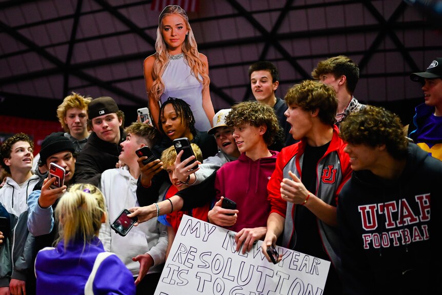 Olivia Dunne, seen from behind, speaks to fans at an NCAA gymnastics meet between LSU and Utah.