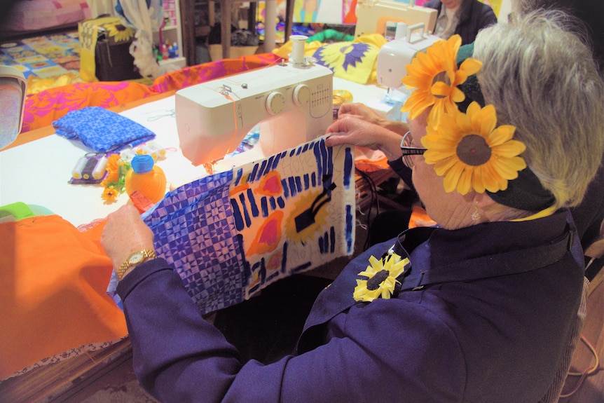 a woman working on a patch at a sewing machine