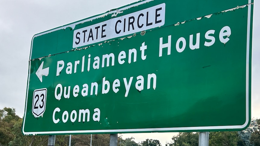 A road sign for 'State Circle', pointing to Parliament House, Queanbeyan and Cooma.