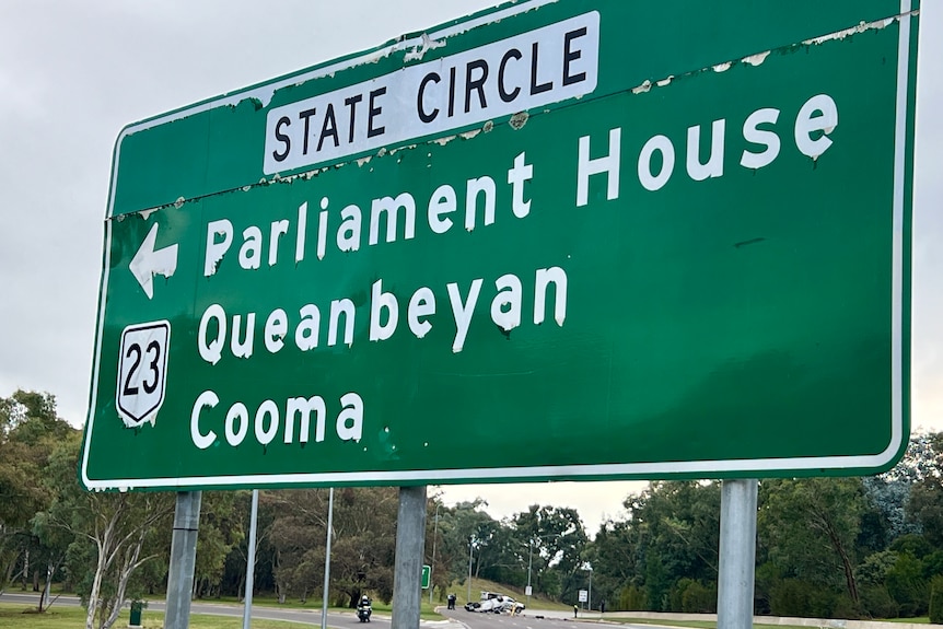 A road sign for 'State Circle', pointing to Parliament House, Queanbeyan and Cooma.