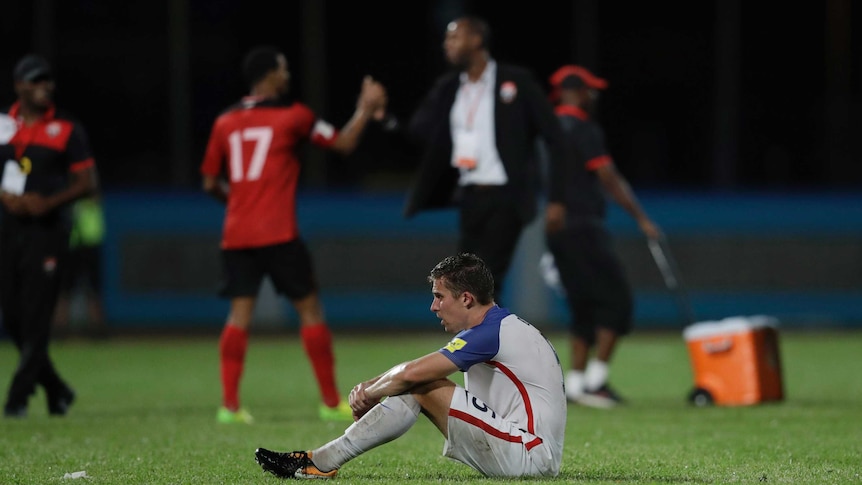 United States' Matt Besler squats on the pitch after losing 2-1 against Trinidad and Tobago.