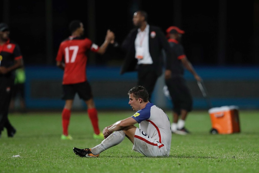 United States' Matt Besler squats on the pitch after losing 2-1 against Trinidad and Tobago.