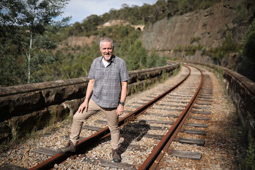 British comedian Griff Rhys Jones standing on rail tracks in the Blue Mountains, NSW.