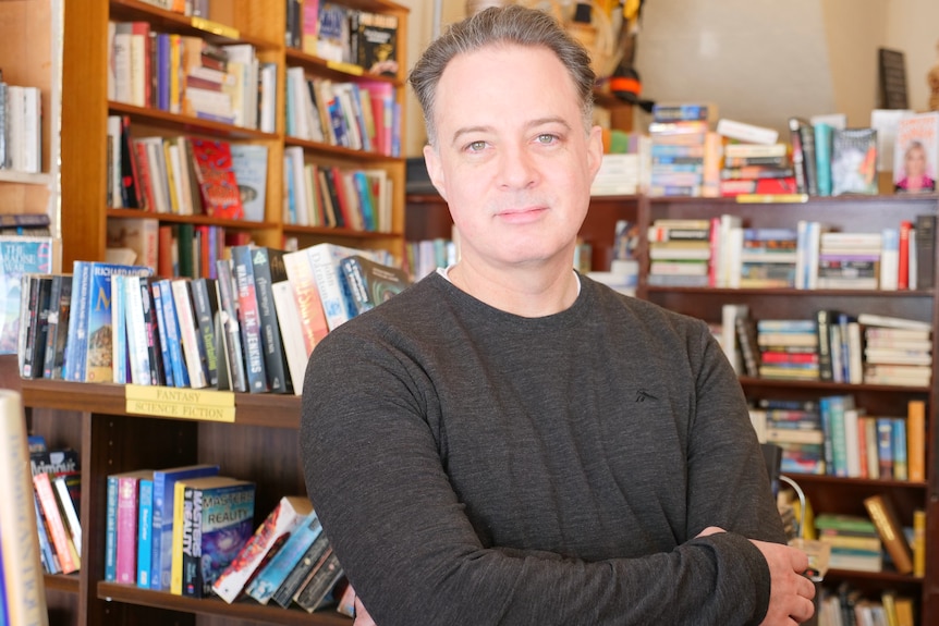A man standing in front of bookshelves full of books.