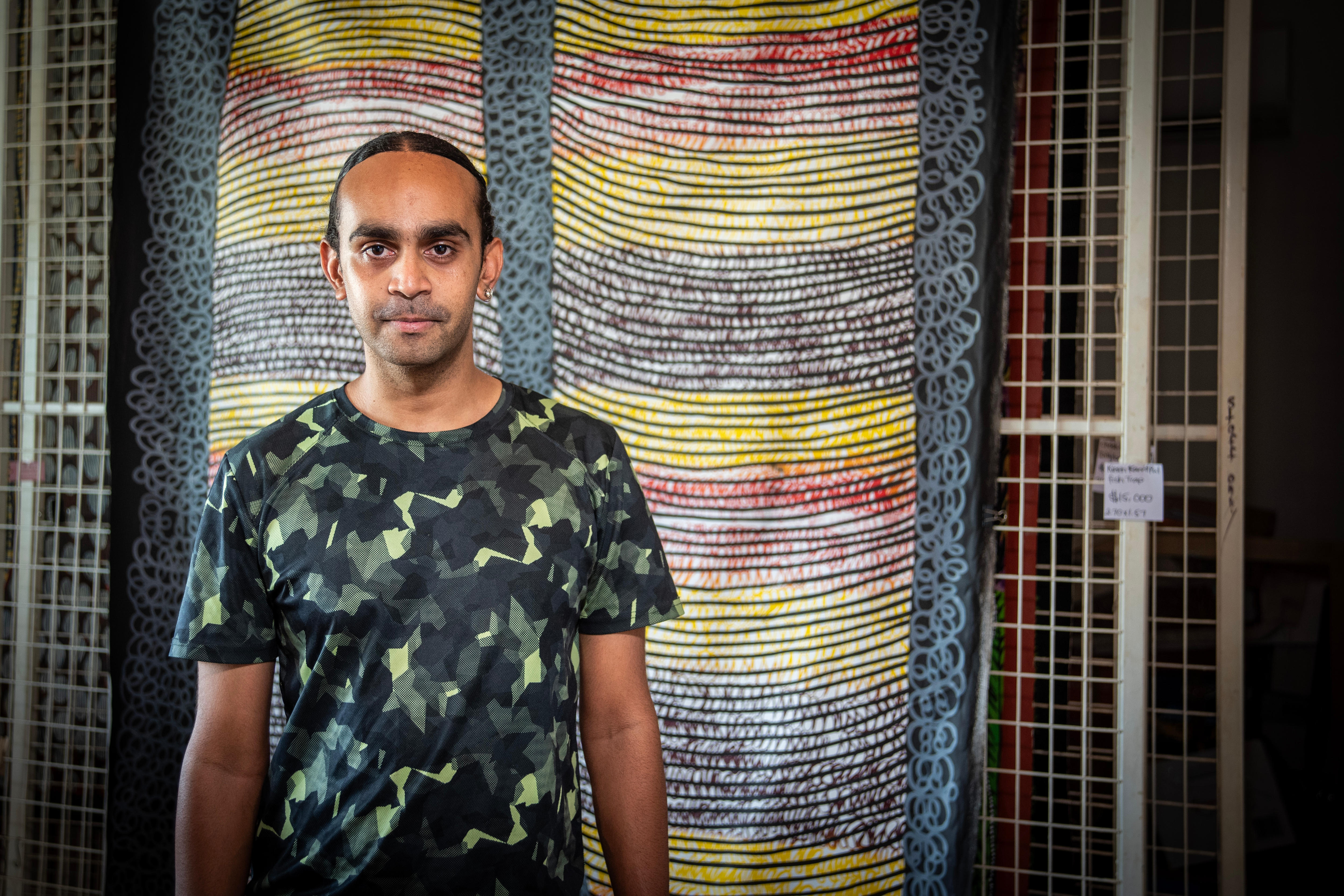 A young man stands in front of a print. 