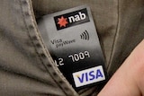 Tap and go credit card pokes out of man's trouser pocket.