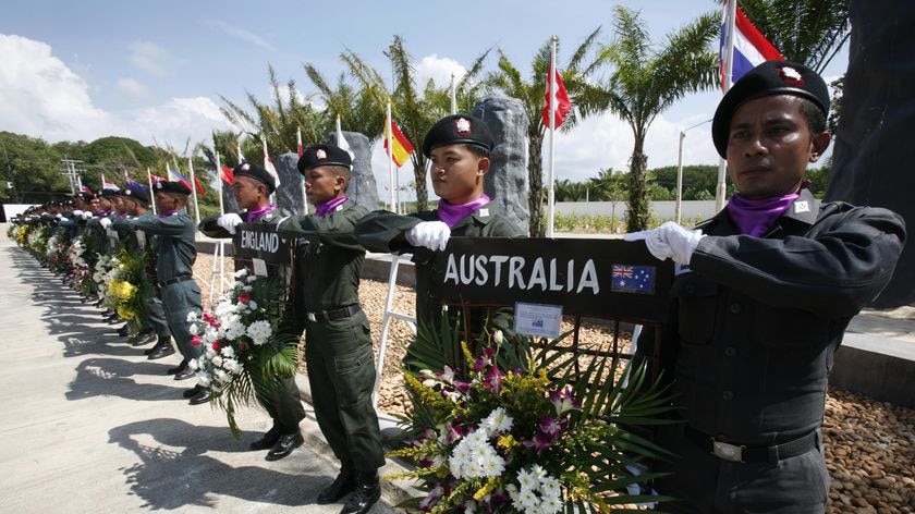 Police officers holds wreaths in front of flags of countries whose nationals died during the Indian