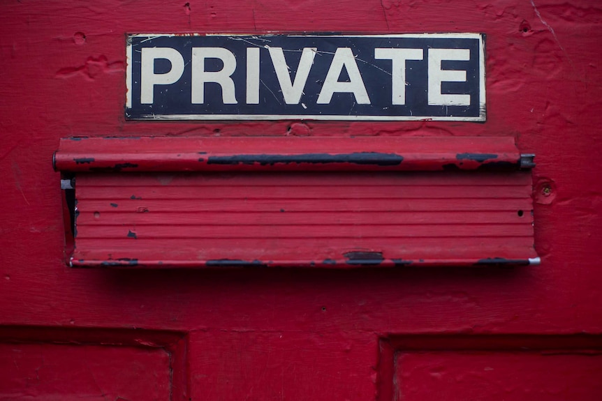 A sign that says "private" on a red wall.