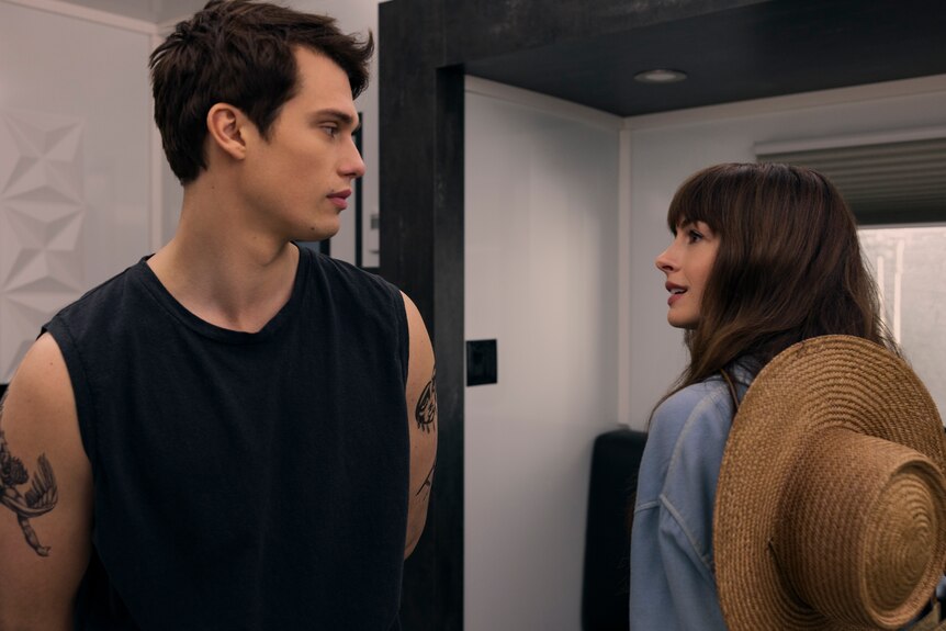 A film still of Nicholas Galitzine, 29, and Anne Hathaway, 41, looking back to check each other out and making eye contact.