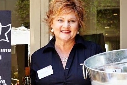 File image of a smiling woman in black work clothing 