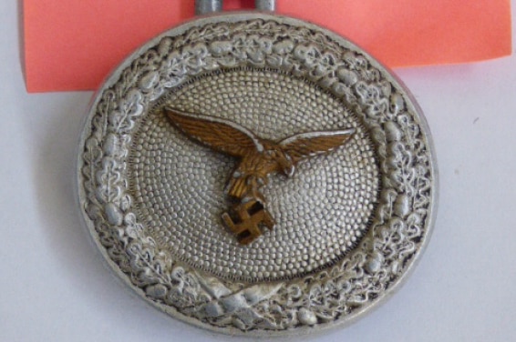 A round badge with an eagle on top of a swastika