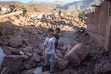 Two boys walk through rubble.