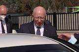 The Governor-General David Hurley wearing a suit and tie hops into a white car in Canberra.