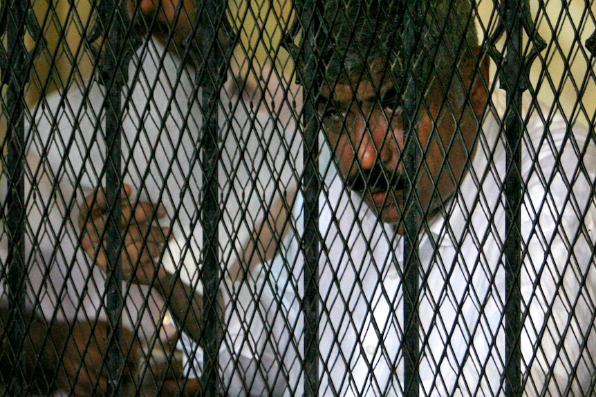 Hesham Talaat Moustafa stands inside a cage at a court in Cairo.