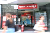 Two blurred people walk pass the Flight Centre shopfront at South Bank in Brisbane.