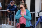 A woman in a tracksuit jacket cries in front of a police barricade at Bondi Junction 