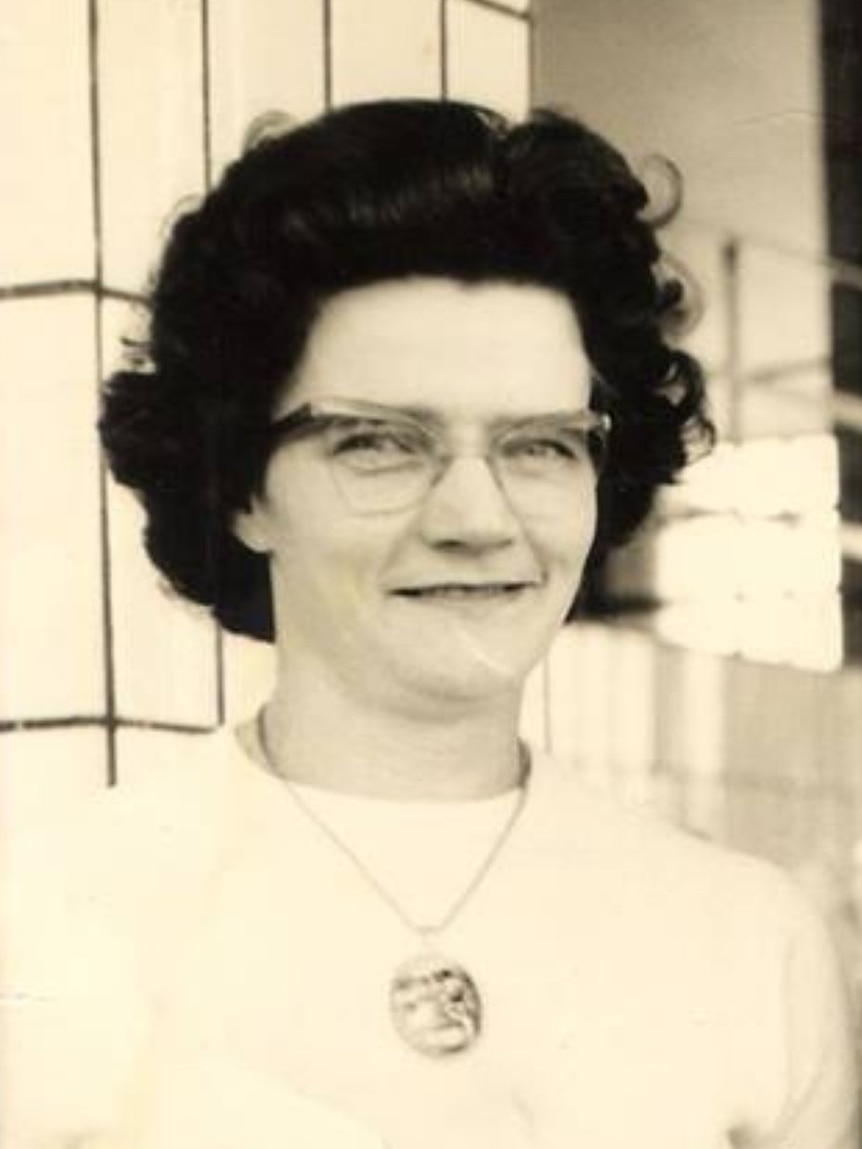B&W Women with black hair glasses and large medallion in white shirt