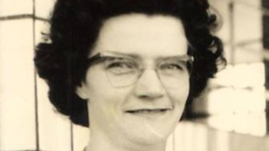 B&W Women with black hair glasses and large medallion in white shirt