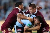 Nathon Cleary of the blues is tackled by two Maroons players