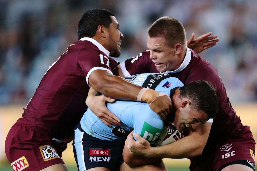 Nathon Cleary of the blues is tackled by two Maroons players