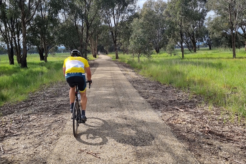 A man on a bike on a dirt path surrounded by grass and trees. Ausnew Home Care, NDIS registered provider, My Aged Care