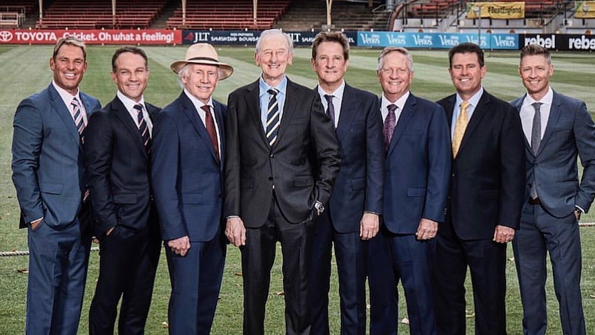 A photo of eight white men dressed in suits from a Wide World of Sports tweet announcing their men's Ashes commentary team.