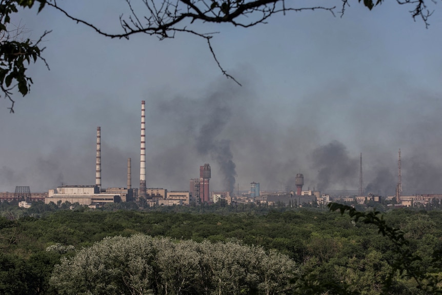 smoke is seen billowing out of a chemical plant from a distance