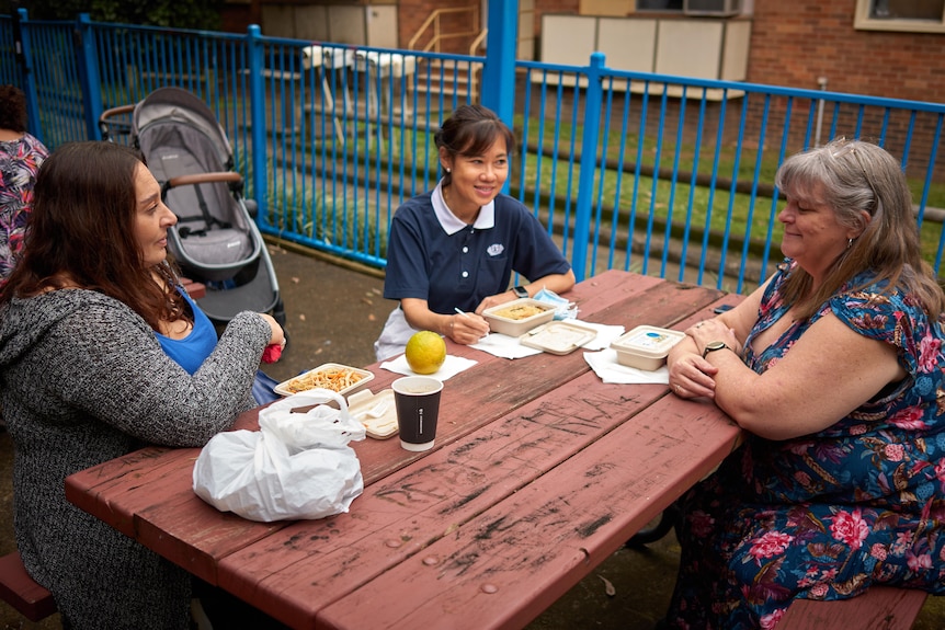 Annette sitting at a table, speaking with Kathryn and another woman while eating.