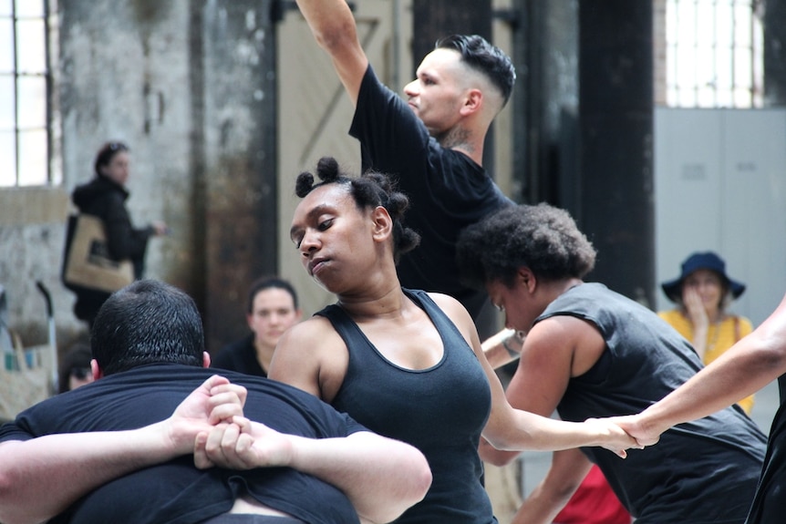 Performers wearing black do modern dance