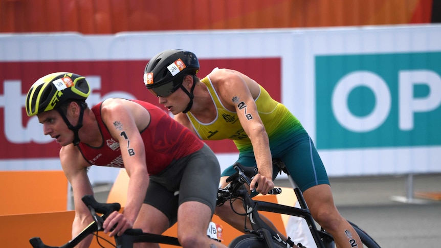 Two triathletes on bikes going around a corner