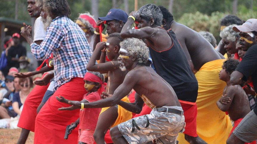 Men and women, some wearing paint, perform a traditional dance at the Garma Festival.