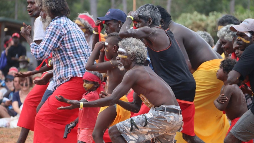 Men and women, some wearing paint, perform a traditional dance at the Garma Festival.