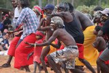 Men and women, some wearing paint, perform a traditional dance at the Garma Festival.