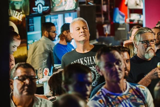 A group of men standing around a bar.