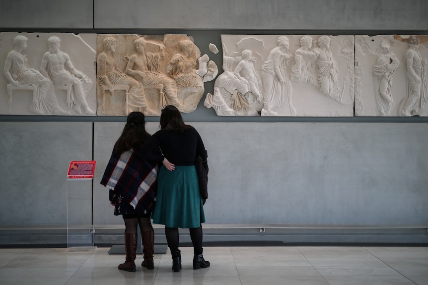 Visitors look at original sculptures and plaster cast copies of the frieze.