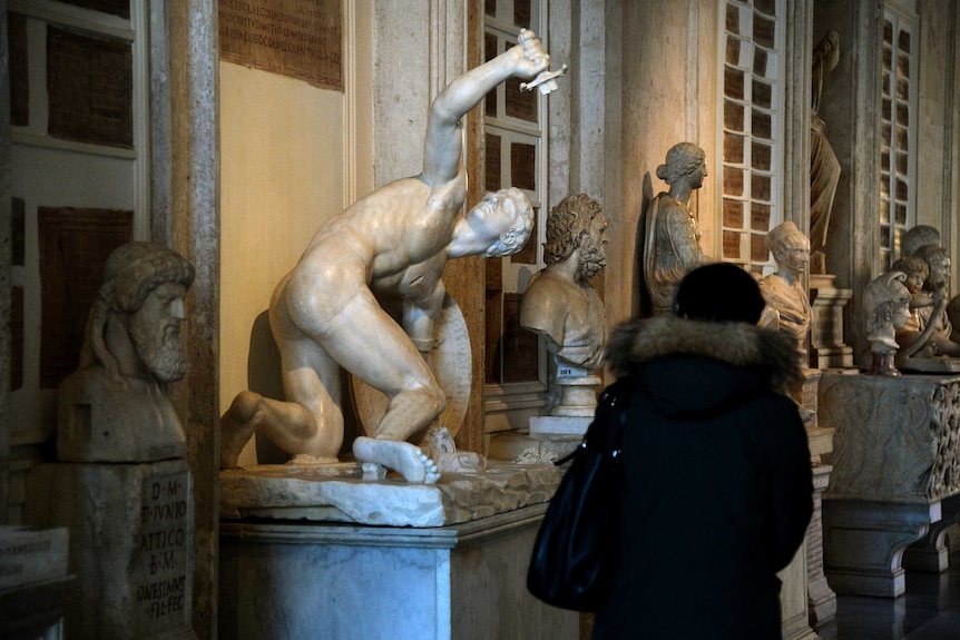 A tourist takes a photo of a nude Roman marble statue at Capitoline Museum