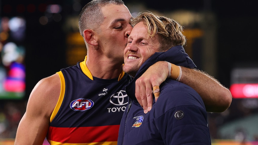 Taylor Walker gives a smiling Rory Sloane a kiss on the cheek