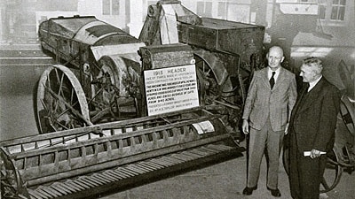 Headlie Taylor pictured in 1915 standing next to the Header he designed in 1914.