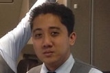 A man in a flight attendant uniform stands at the meal preparation area of a plane.