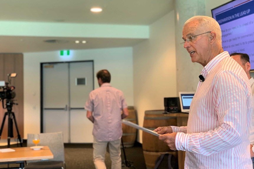 A man reads off a piece of paper while standing up.