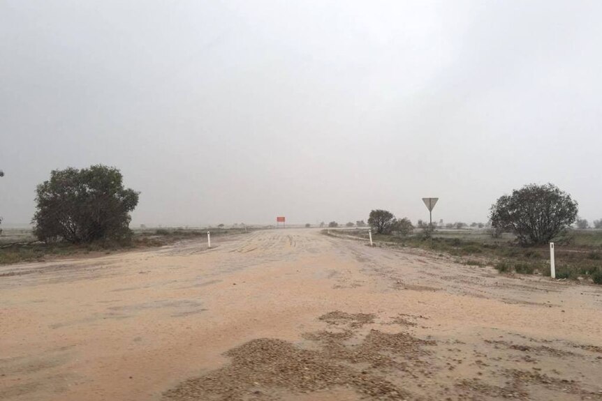 A wet, dirt road leading into and out of Birdsville in Western Queensland