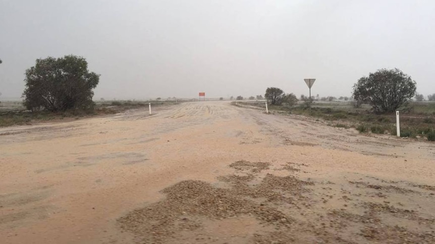 A wet, dirt road leading into and out of Birdsville in Western Queensland