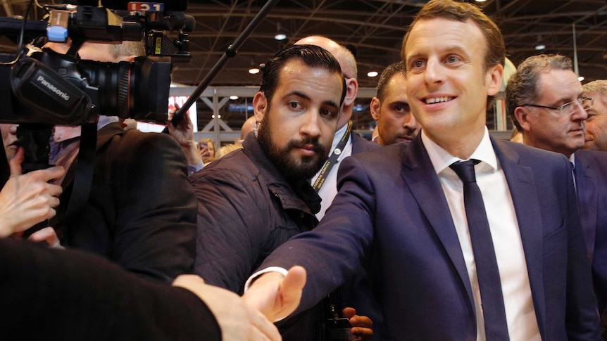 Alexandre Benalla stands between French President Emmanuel Macron and a media pack