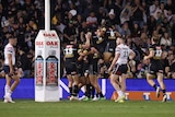 Penrith Panthers players jump on each other in celebration next to the goalposts after a try against the Roosters.