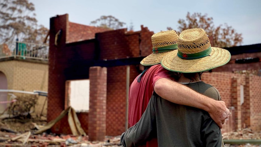 Man and woman look at their burnt out home