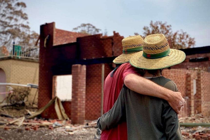 Man and woman look at their burnt out home