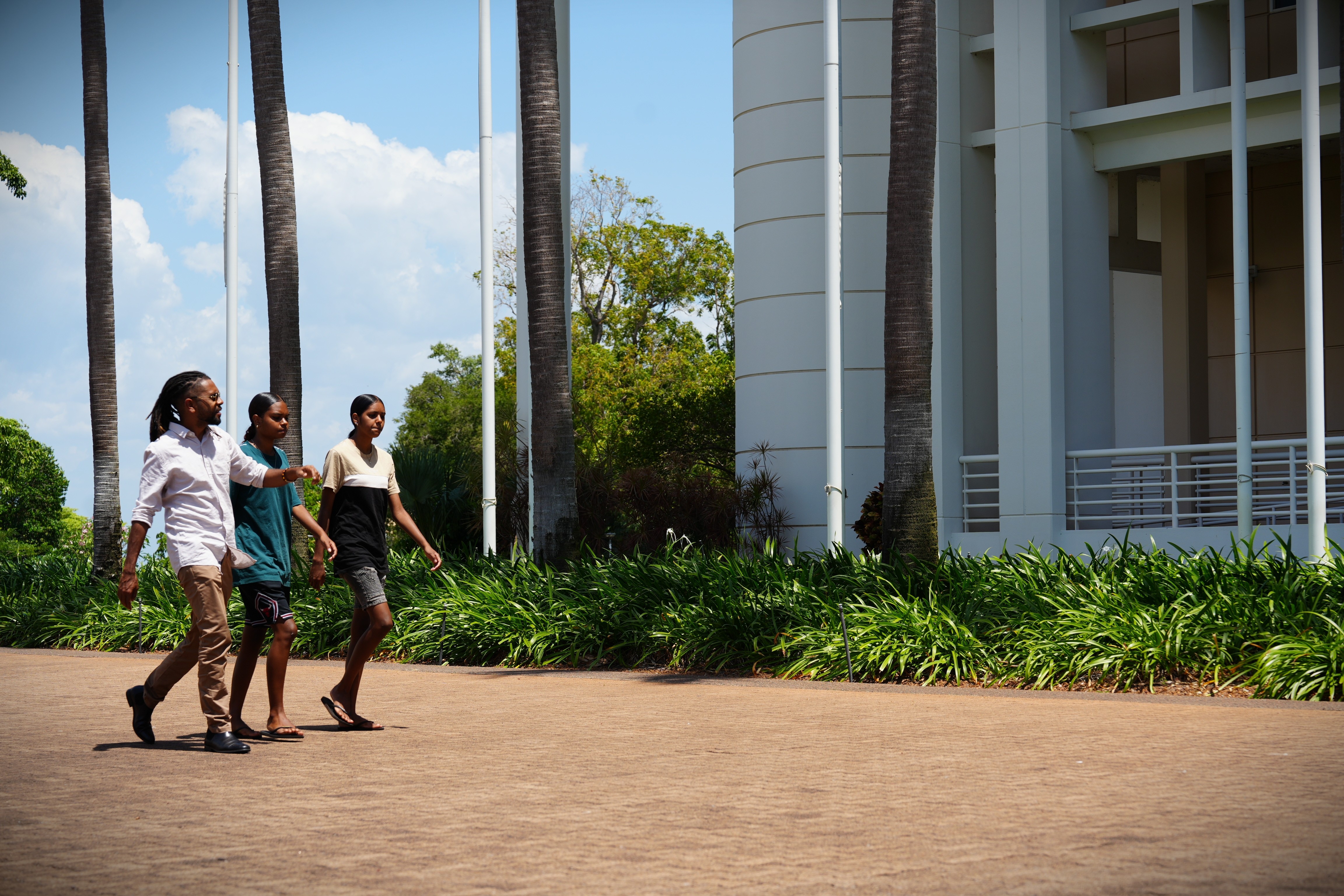 A man walks with his two daughters towards the steps of the NT's parliament