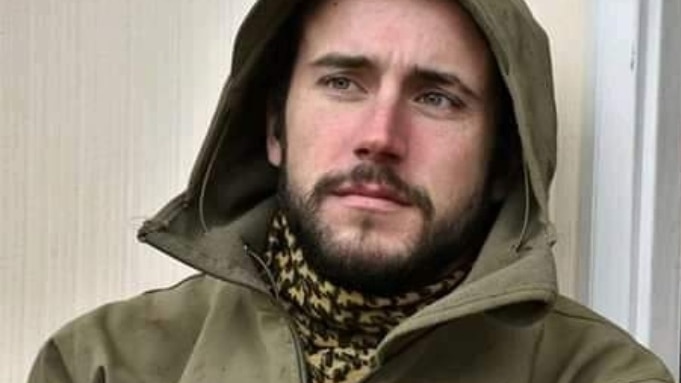 Aleziah Spiers wearing a subdued-green jacket with a hood and a scarf, looking away from the camera.