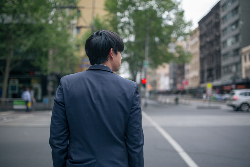 A businessman waits to cross the road in Melbourne.
