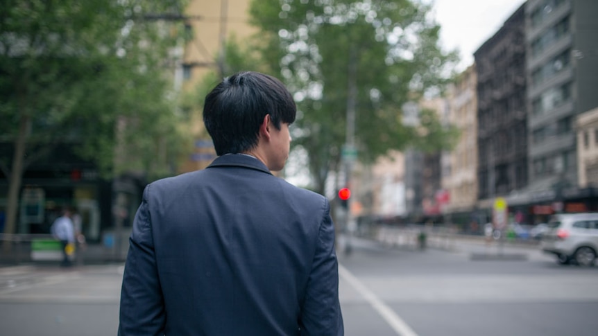 A businessman waits to cross the road in Melbourne.
